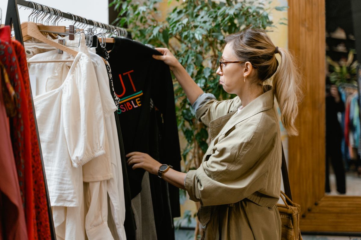 Fashion enthusiast browsing clothing rack in boutique store, selecting attire.