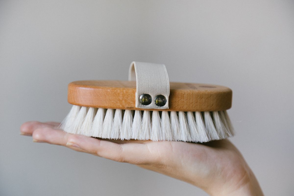 A detailed close-up of a wooden shoe brush resting on a person's hand, highlighting its design.