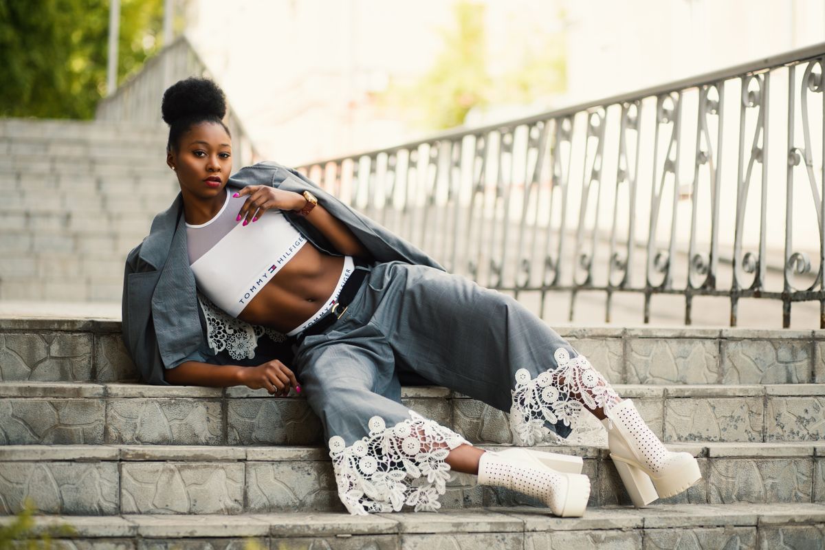 Elegant woman in trendy attire poses confidently on outdoor stairs, displaying modern fashion.