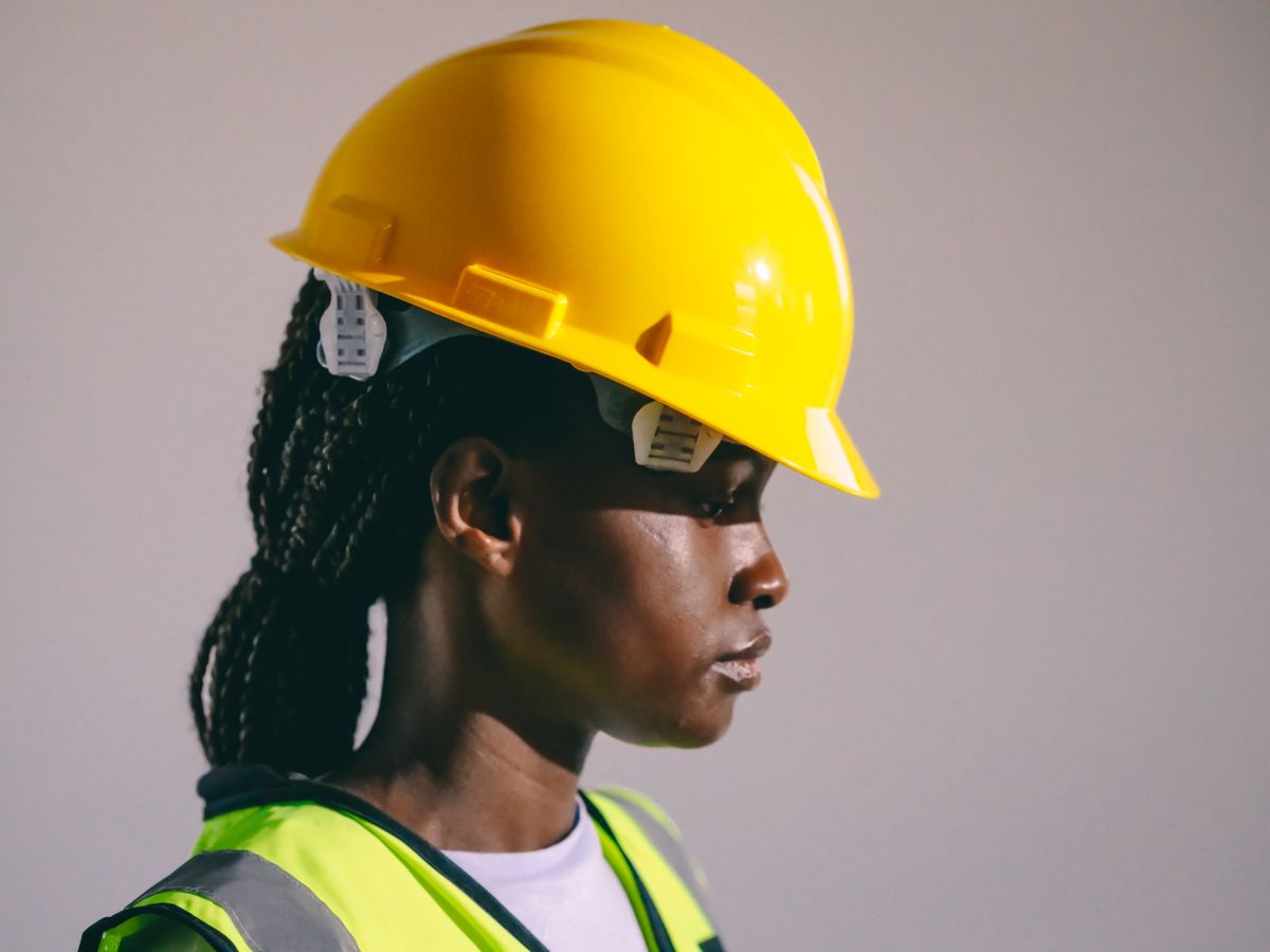 Side view of a woman engineer wearing a yellow hard hat and reflective vest, showcasing safety in engineering.