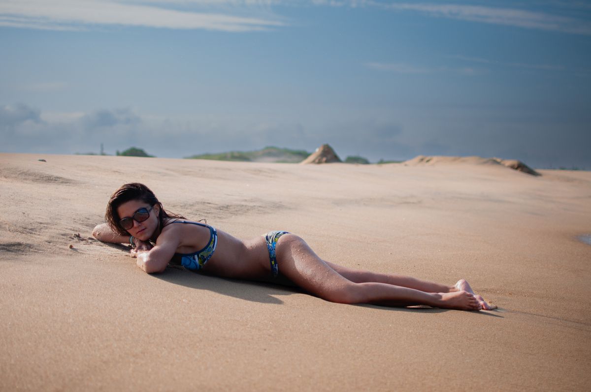 Woman lying on a sunny beach in summer, enjoying the outdoors.