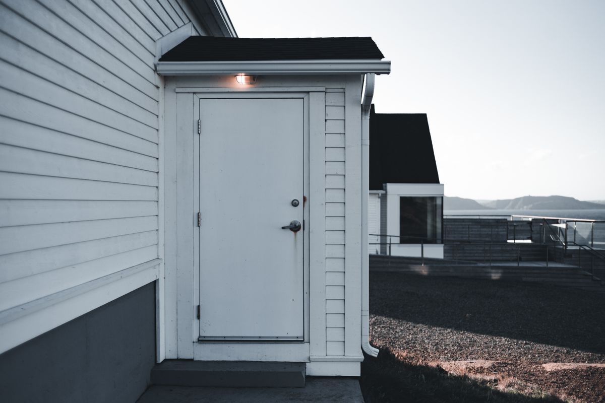 A minimalist white door on a modern building exterior with a sleek, clean design captured in soft lighting.