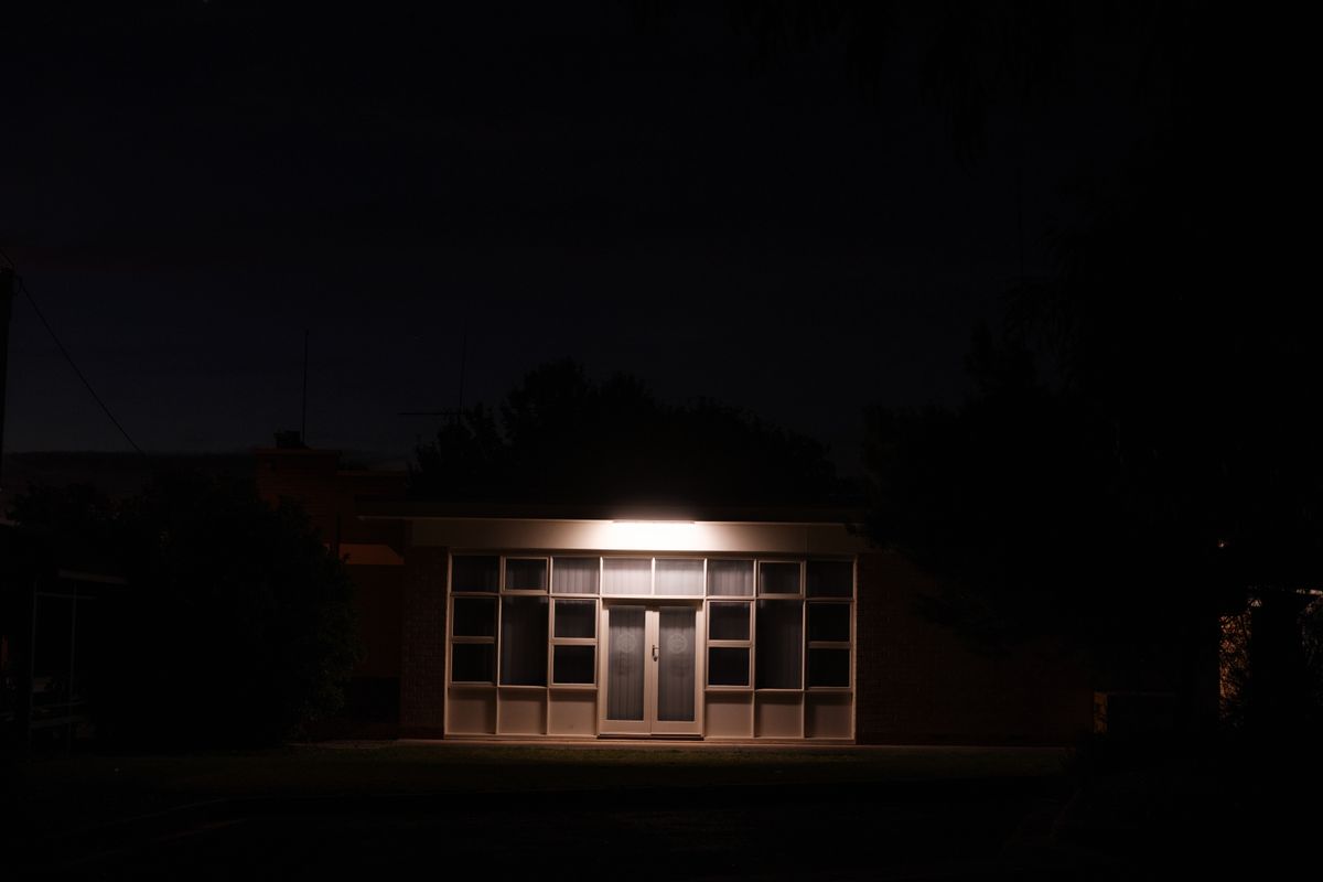 A secluded building entrance is illuminated by a single light in the darkness of night, creating a mysterious atmosphere.