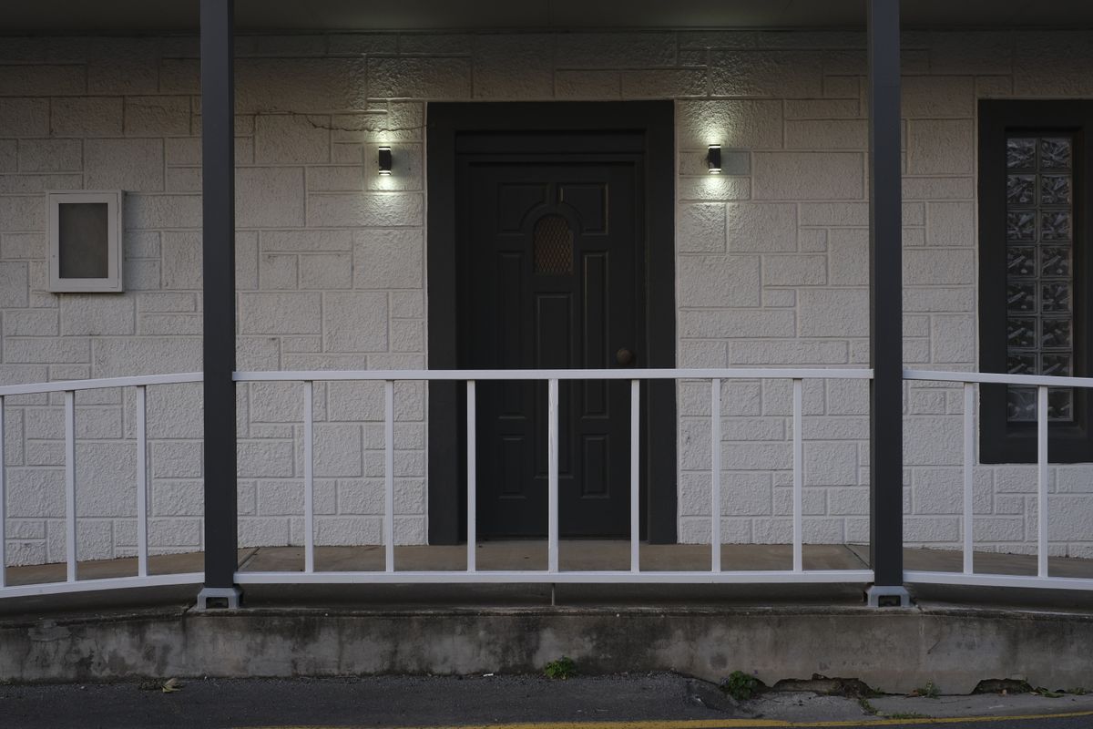 Front view of a modern house entrance featuring white railing and dark door, perfect for architectural studies.