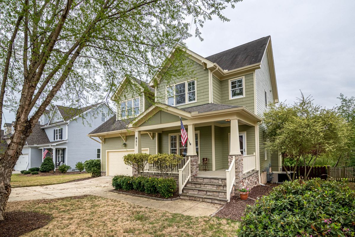 Spacious suburban house with porch, garden, and American flag, perfect for real estate listings.