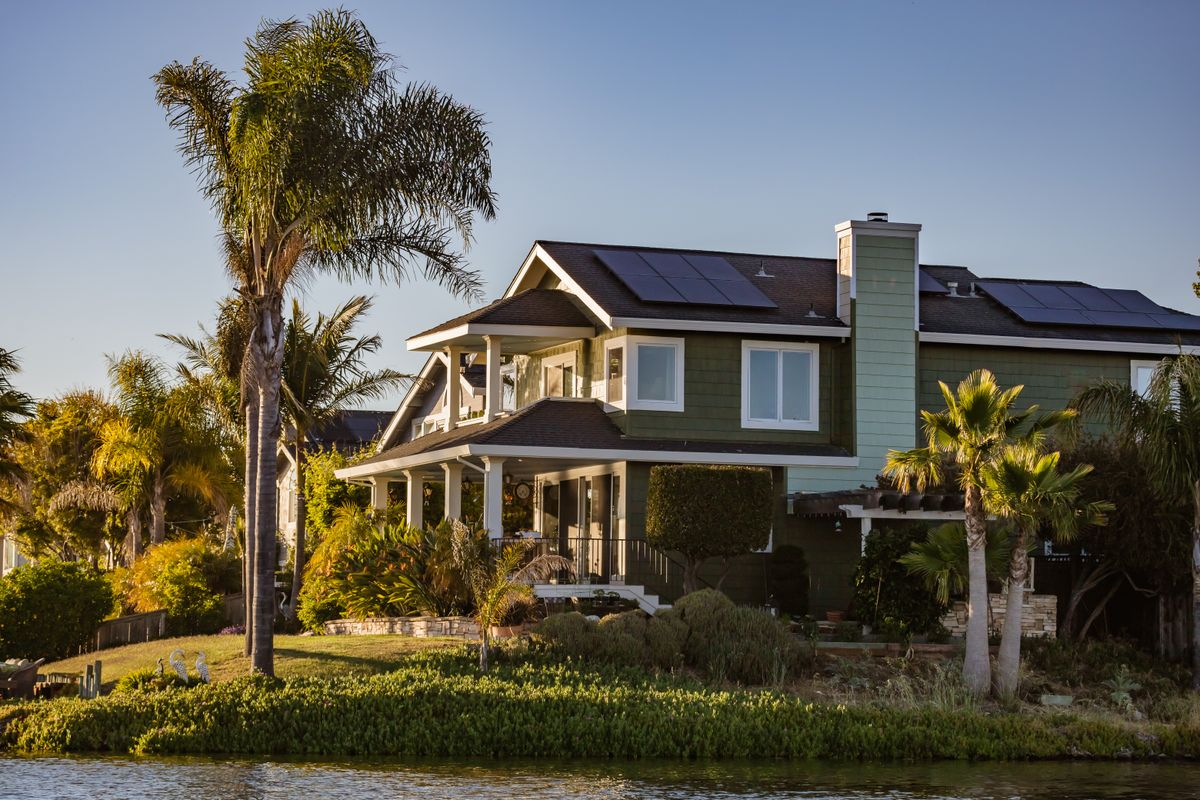 Contemporary home with solar panels and lush garden by the river.