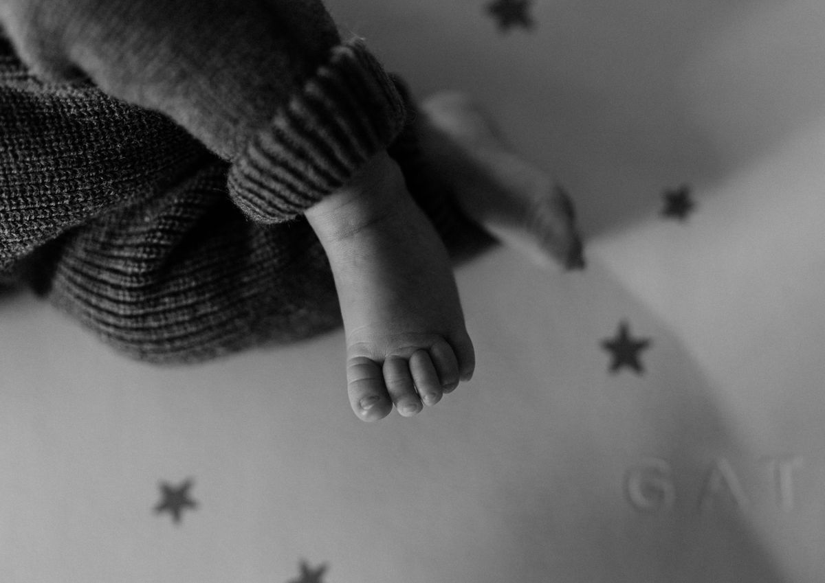 Monochrome image of a baby's foot in a knitted romper, artistic composition.