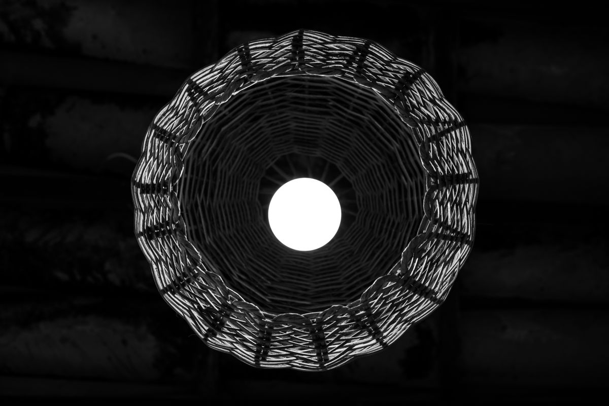 A striking overhead view of a woven basket lamp with dramatic lighting creating a circular pattern.