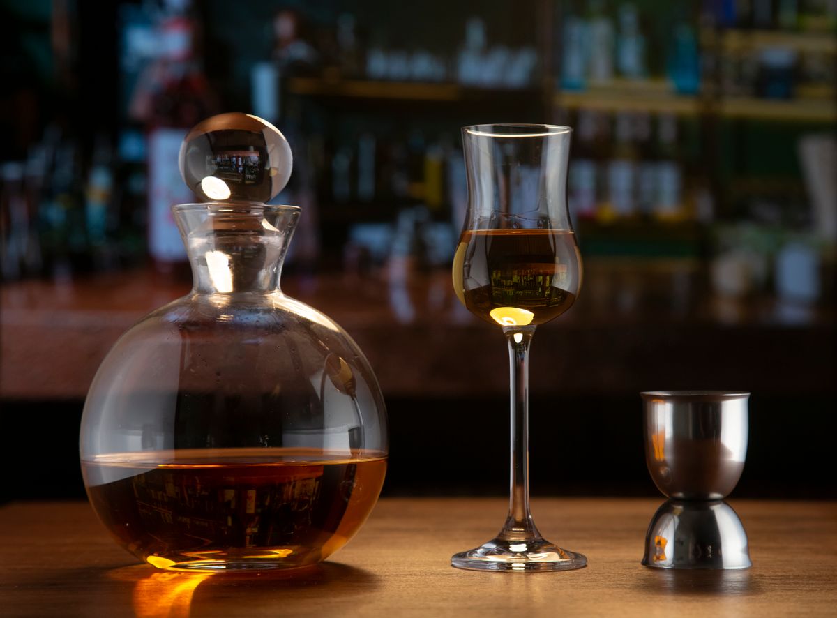 An elegant setup featuring a glass decanter with brandy and a glass on a bar counter.