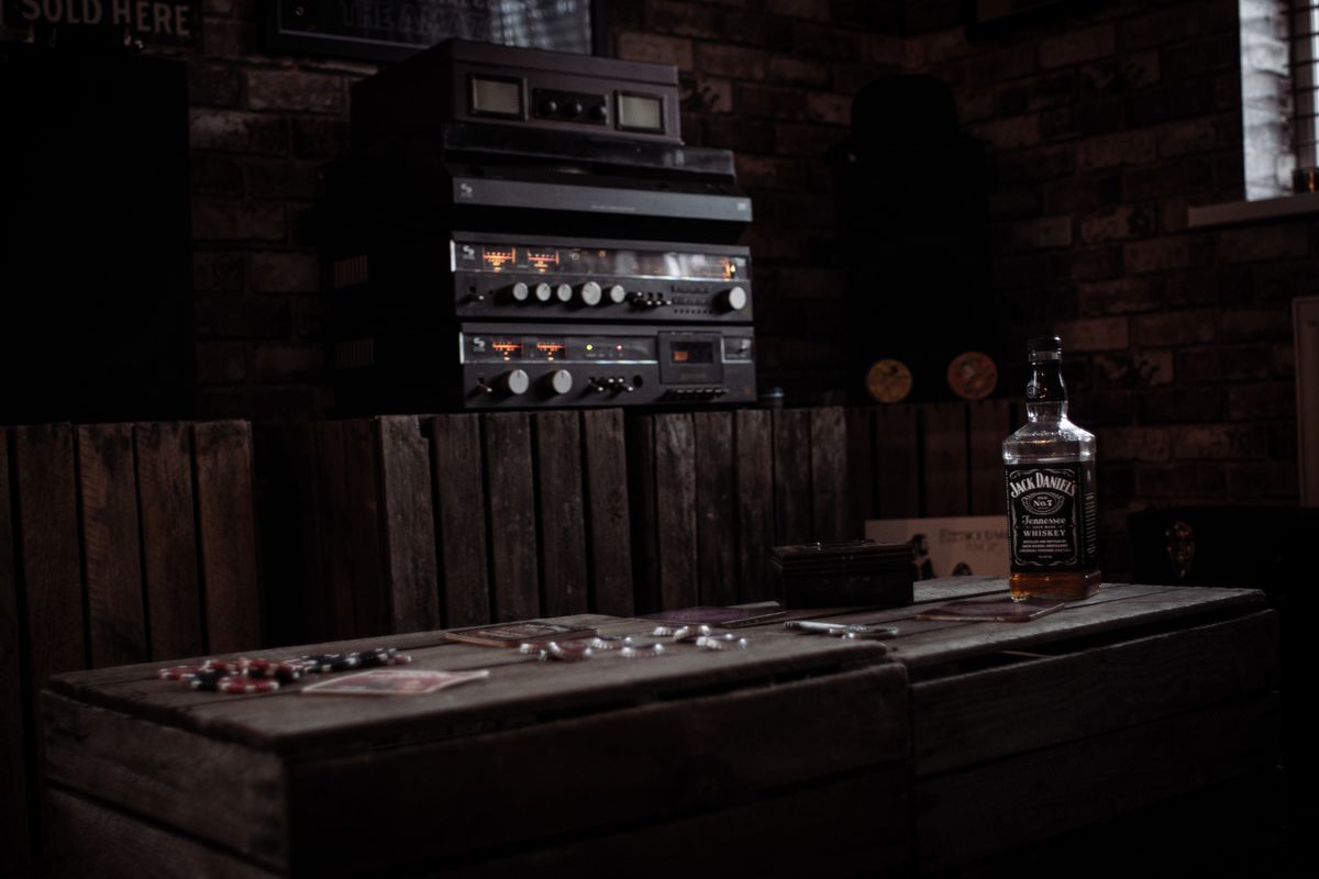 Cozy bar interior with a whiskey bottle on a wooden table and a vintage stereo setup.