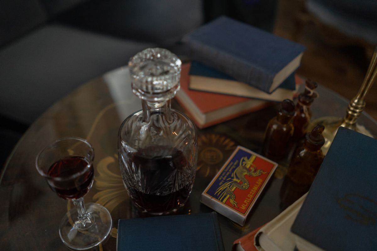 Elegant still life featuring a crystal decanter, wine glass, and vintage books on a wooden table.