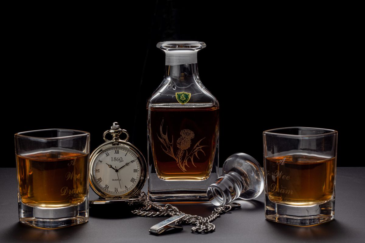 Still life of whiskey glasses and pocket watch on a table, perfect for a classic or vintage theme.