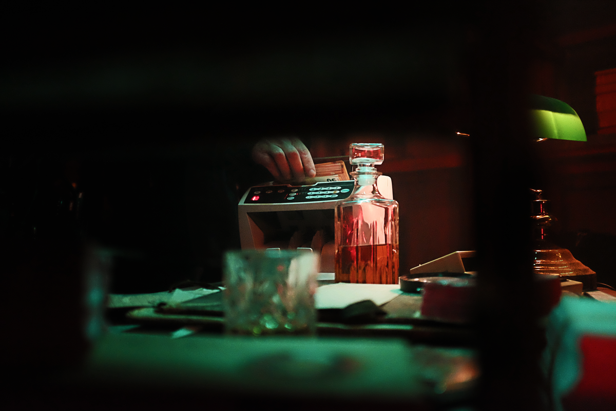 A dimly lit bar scene with whiskey, cash counting, and a vintage ambiance.