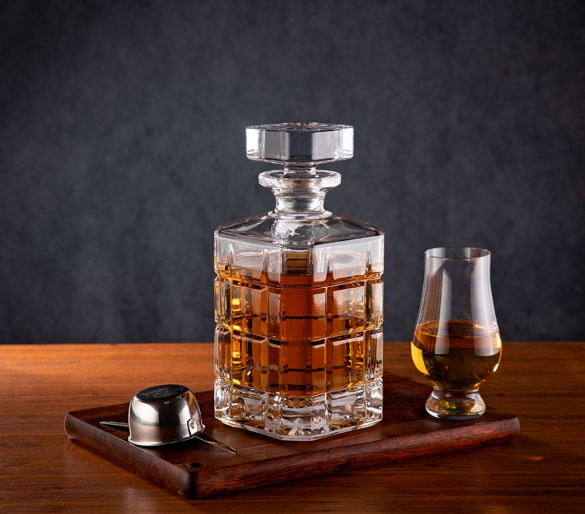 Luxurious whiskey decanter and glass on a wooden tray. Perfect for refined drink settings.