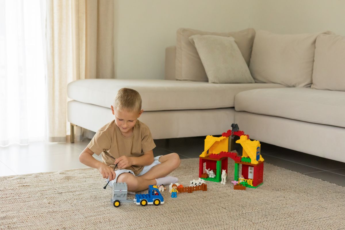 A child enjoys playtime with toy trucks and blocks in a cozy living room setting.