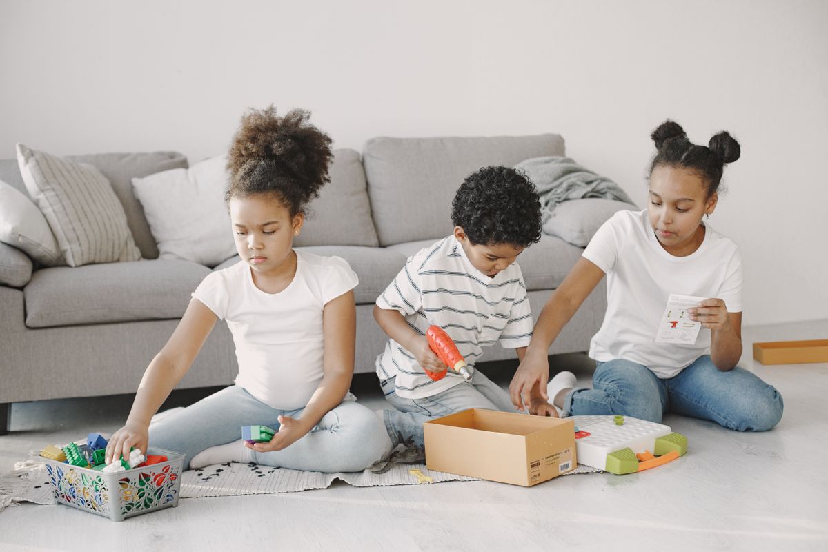 Three children engaged in playing with educational building toys in a cozy living room setting.