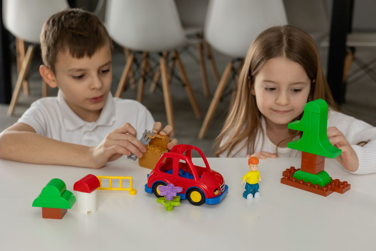 Two children engaged in creative play with colorful building blocks and toys indoors.
