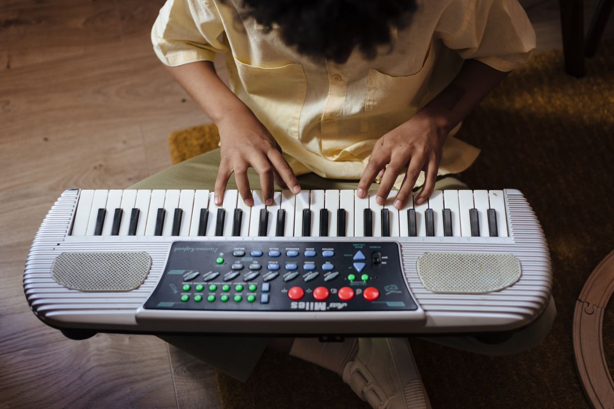 Child playing a small keyboard indoors, focusing on learning and music. Perfect for education and lifestyle themes.