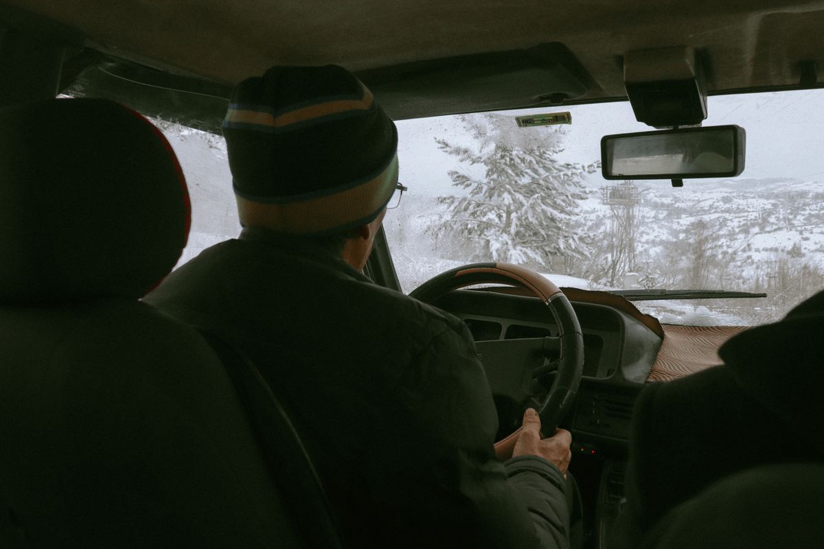 Driver navigating snowy winter landscape from vehicle's interior view.
