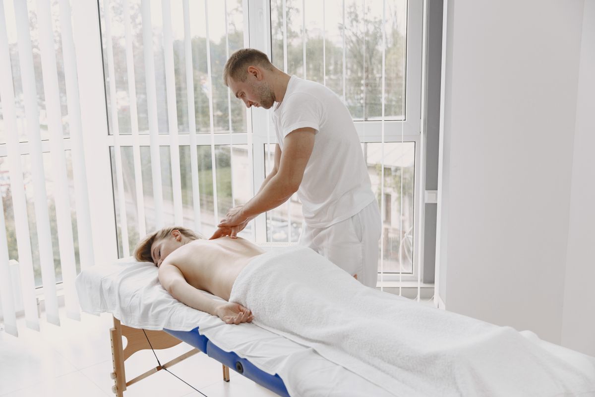 A serene massage therapy session with a masseur providing relaxation to a woman in a spa setting.