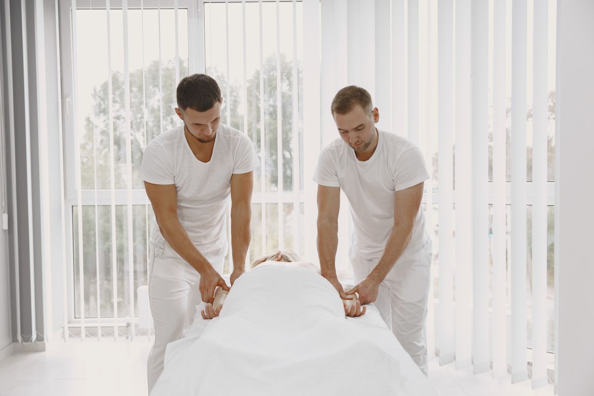 Two male massage therapists perform therapy in a bright, modern spa room promoting relaxation.