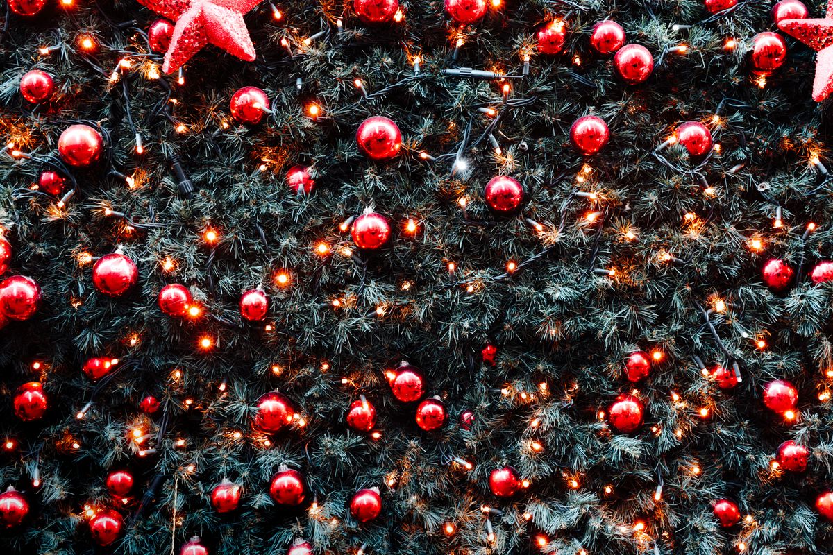Vibrant Christmas tree adorned with red ornaments and warm lights, creating a festive atmosphere.