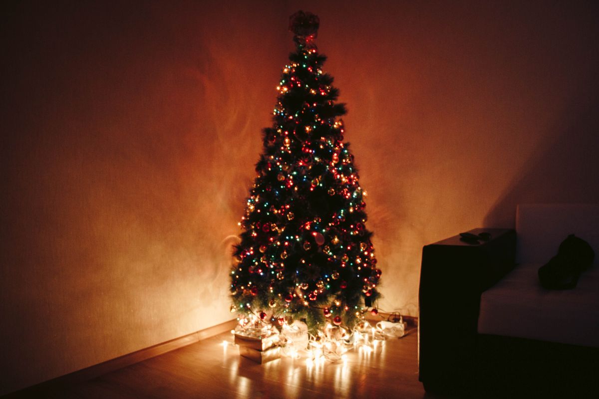 Elegant Christmas tree with vibrant decorations and glowing lights in a cozy indoor setting.