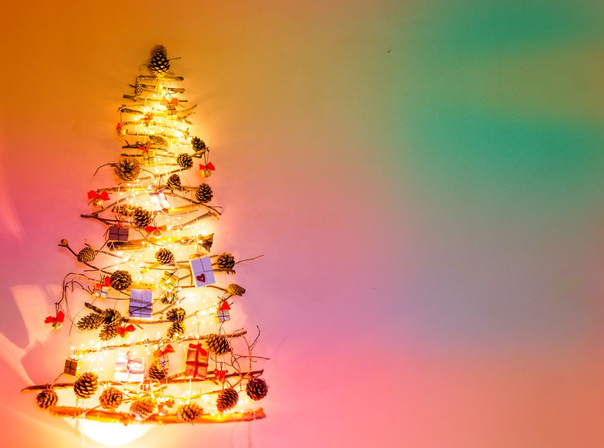 Unique wall-mounted Christmas tree with bright fairy lights and pinecone decorations, perfect for vibrant holiday decor.