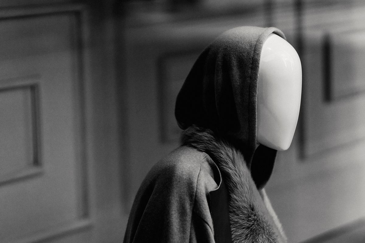 Black and white of mannequin in stylish hooded coat in showcase of modern fashion boutique