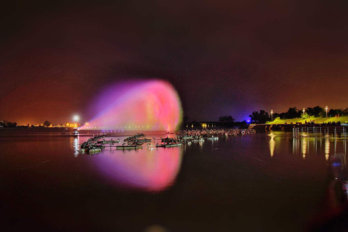 A colorful nighttime water fountain display reflecting on a tranquil lake.