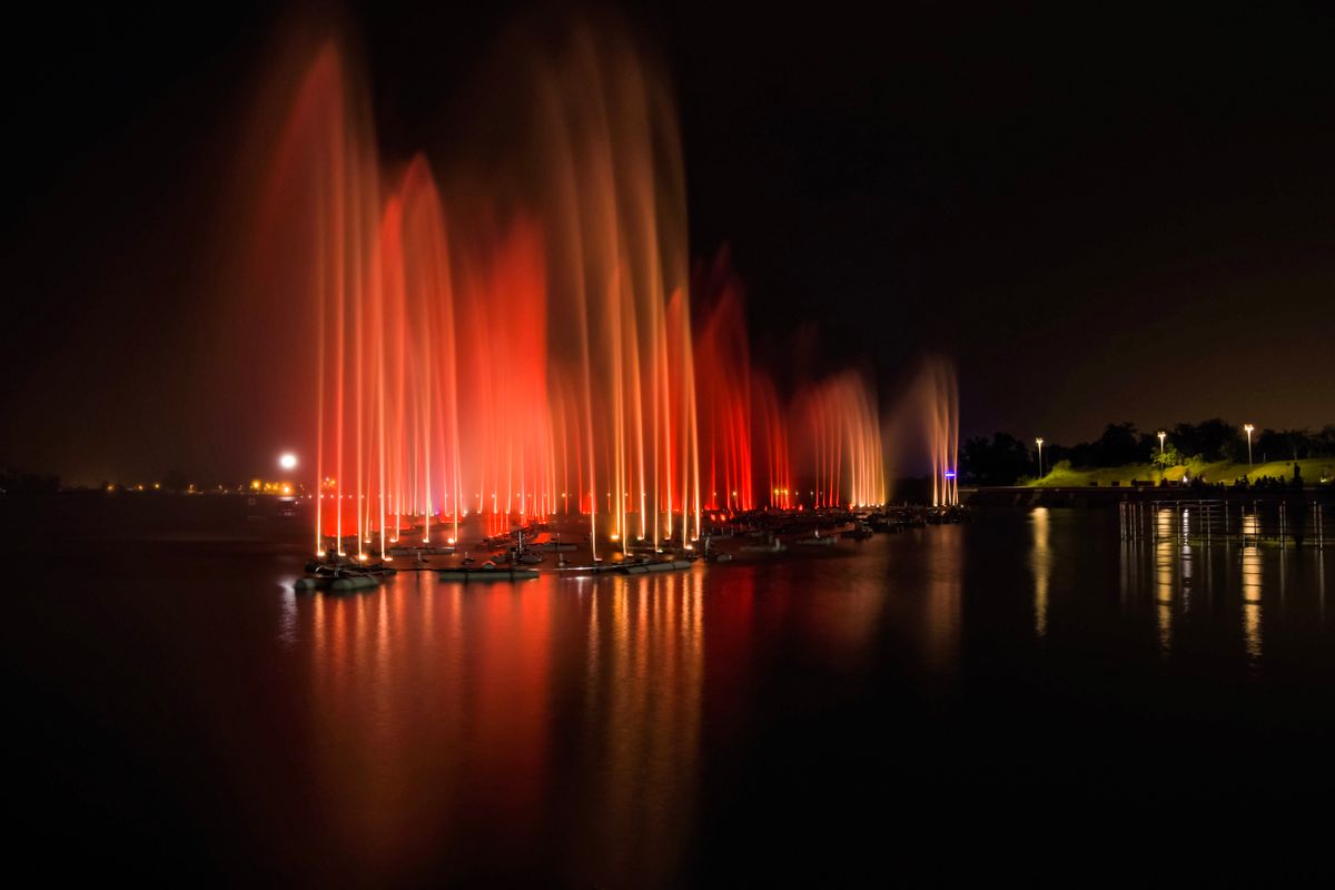 Stunning illuminated water fountain display at night with colorful lights reflecting on water.