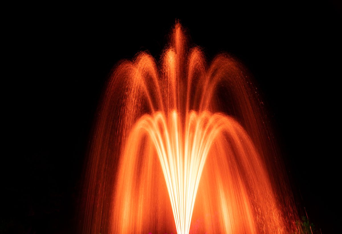 A vibrant night shot of an illuminated fountain with cascading water arcs.