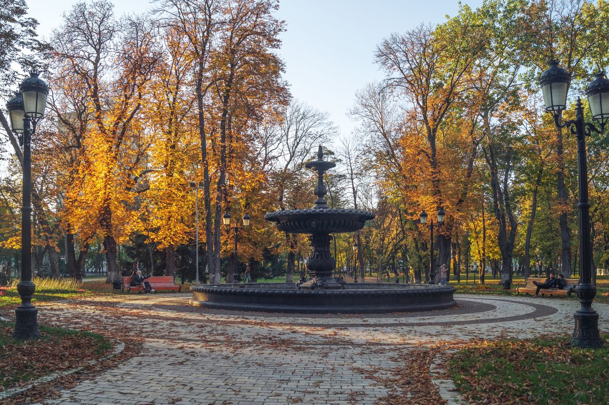 A serene autumn scene with a water fountain in a park in Kyiv, surrounded by vibrant fall foliage.