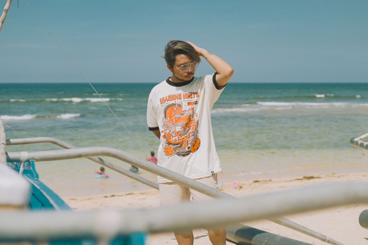 Casual style at the beach with a young man in a graphic tee, enjoying the seaside summer vibe.