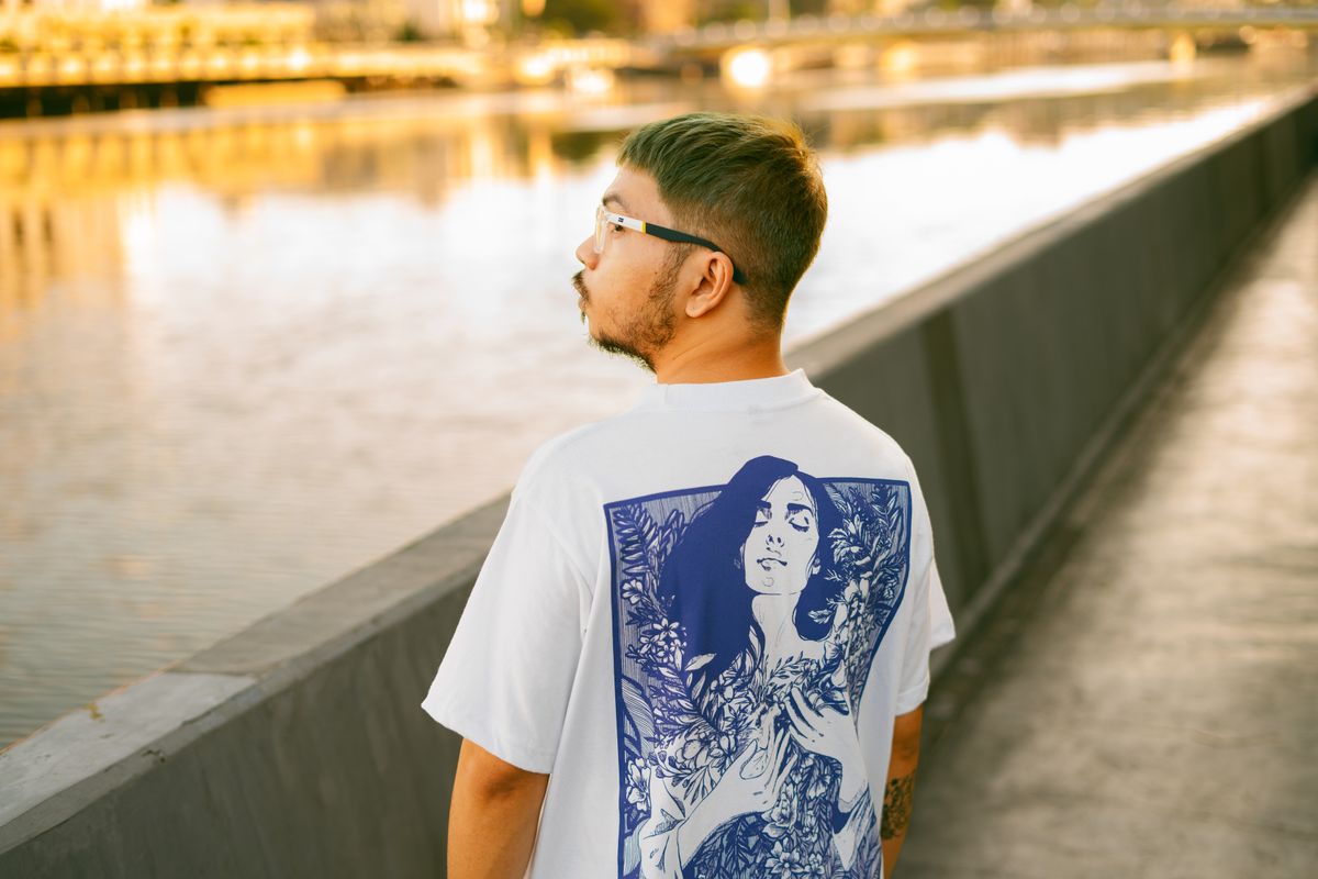A stylish man wearing an artistic t-shirt beside Pasig River in Manila during a sunny day.