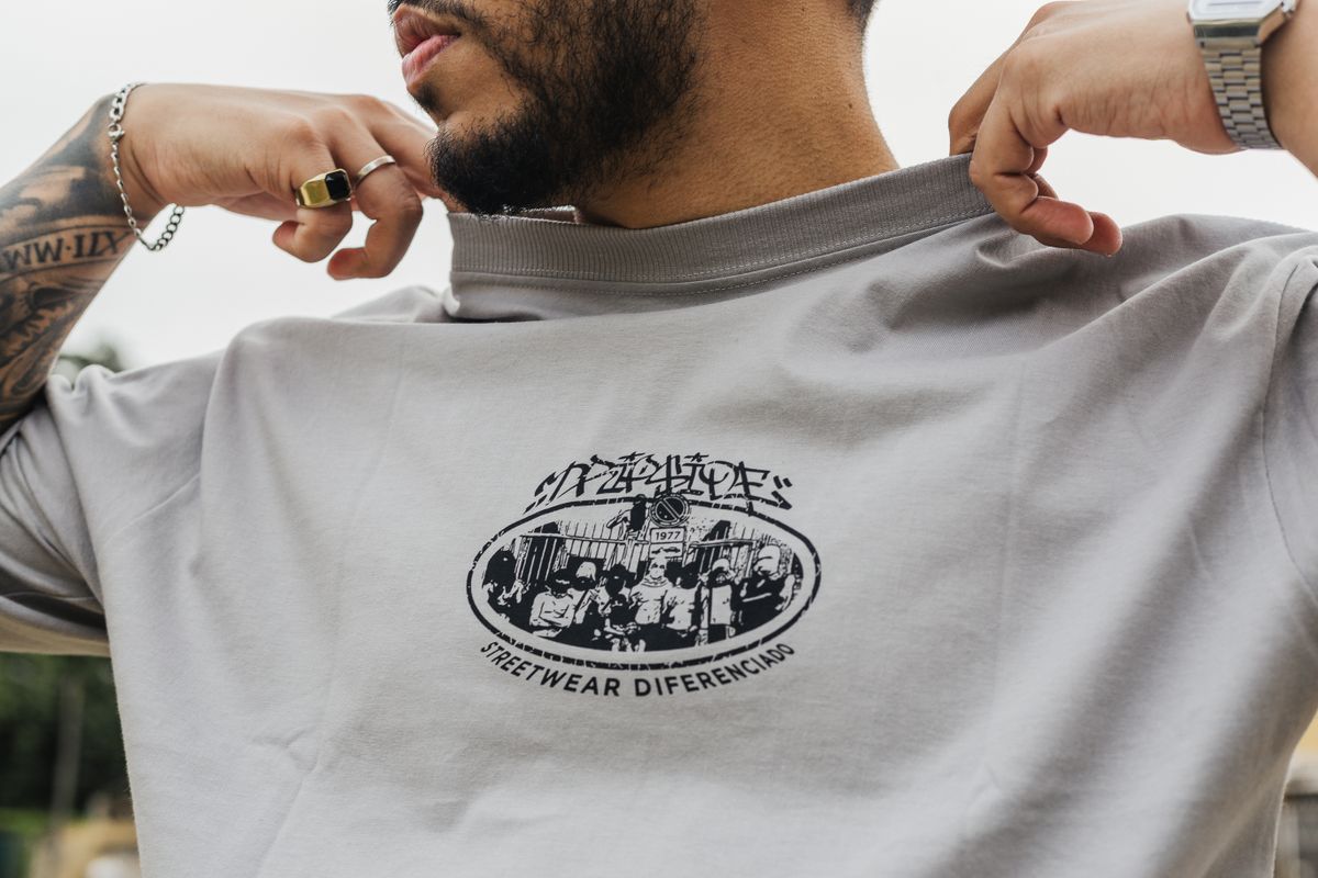 A fashionable man displays a graphic streetwear t-shirt outdoors in São Paulo, Brazil.
