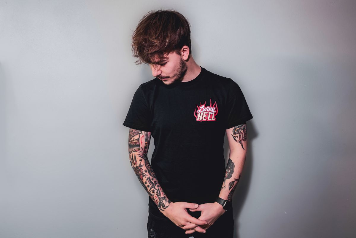 Stylish young man with tattoos wearing a black shirt in a studio setting.