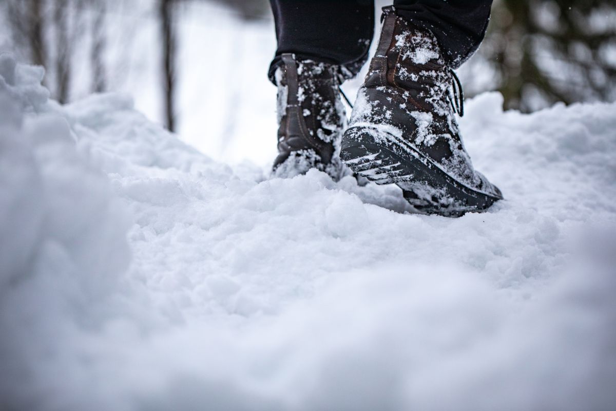 Close-up of boots stepping in deep snow, showcasing winter footwear in a snowy landscape.
