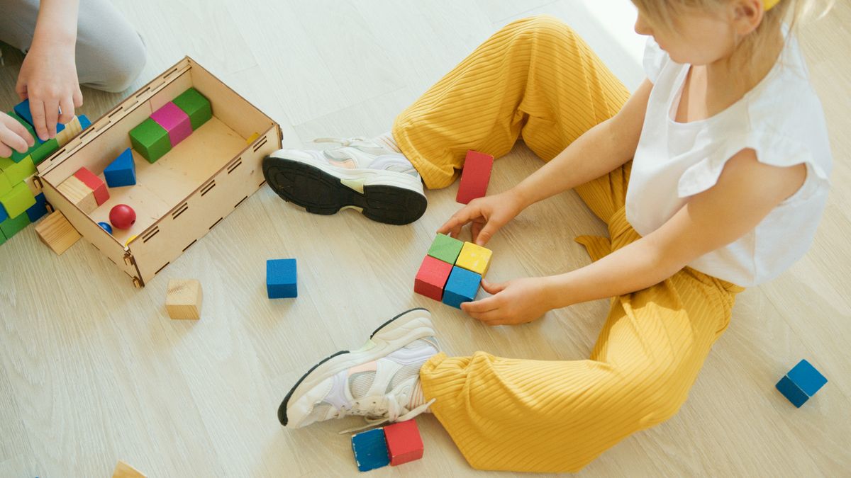 A young child playing creatively with colorful wooden blocks indoors, fostering learning and development.