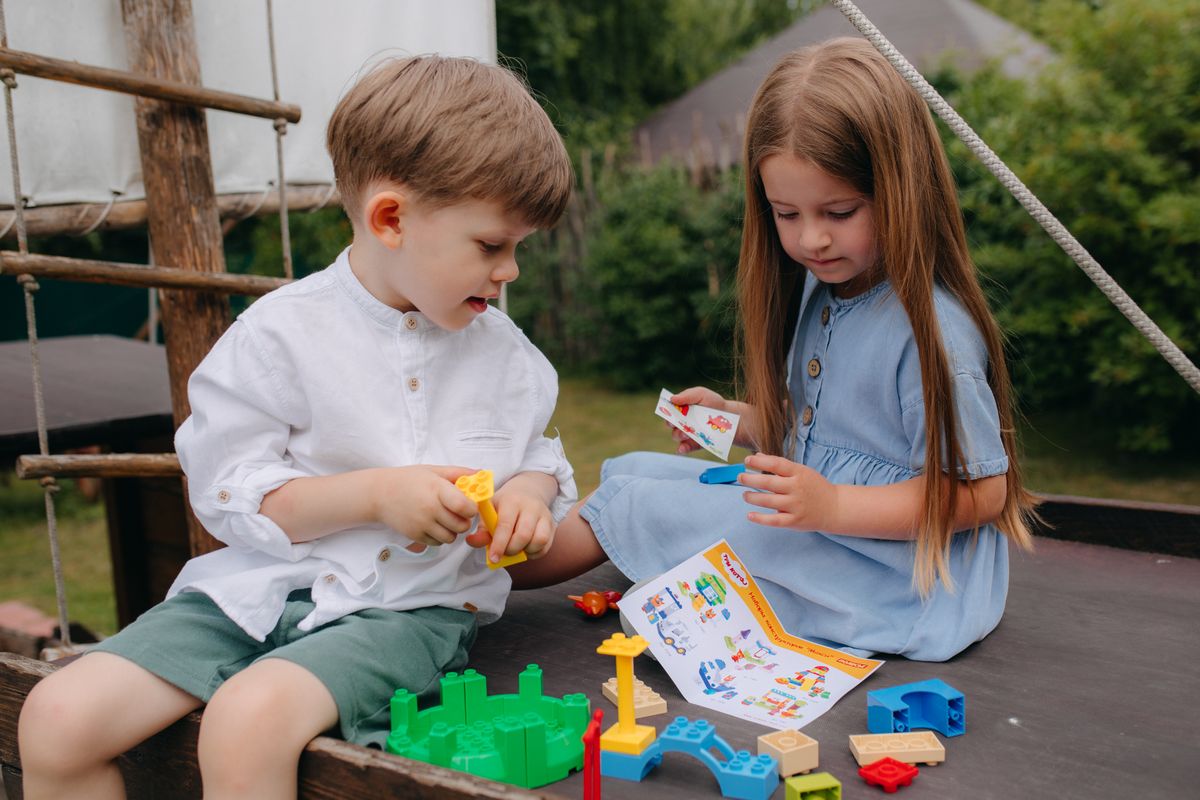 Two children enjoy playing with colorful building blocks on a sunny day.
