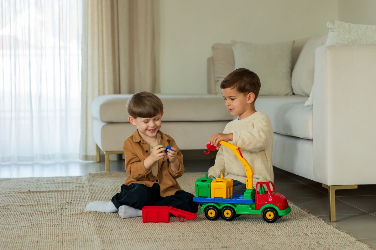 Two young boys enjoying playtime with a colorful toy truck in a modern indoor setting.