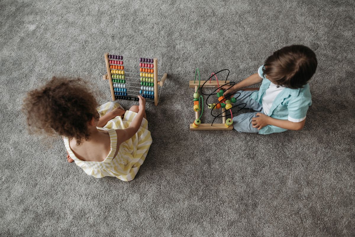 Two children enjoy educational play with a colorful abacus and wooden toy.