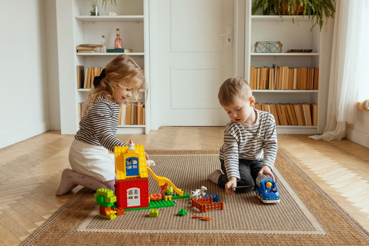Two children building and playing with colorful blocks indoors, creating a playful and warm atmosphere.