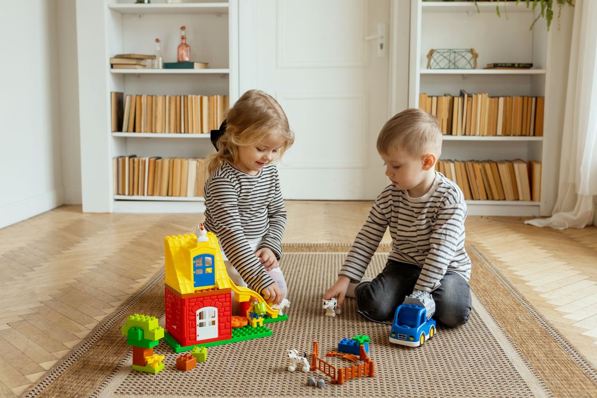 Two children enjoying playtime with colorful building toys in a cozy living room.