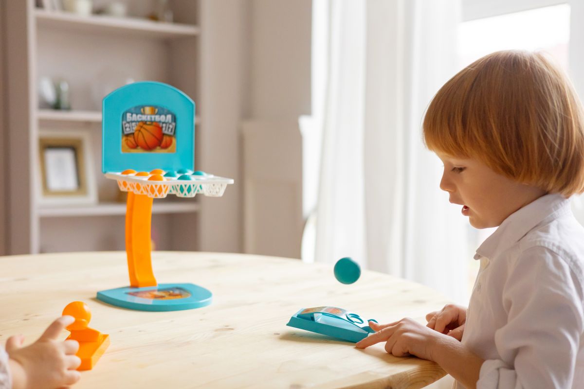 Child enjoying mini basketball game at home, focused and playful
