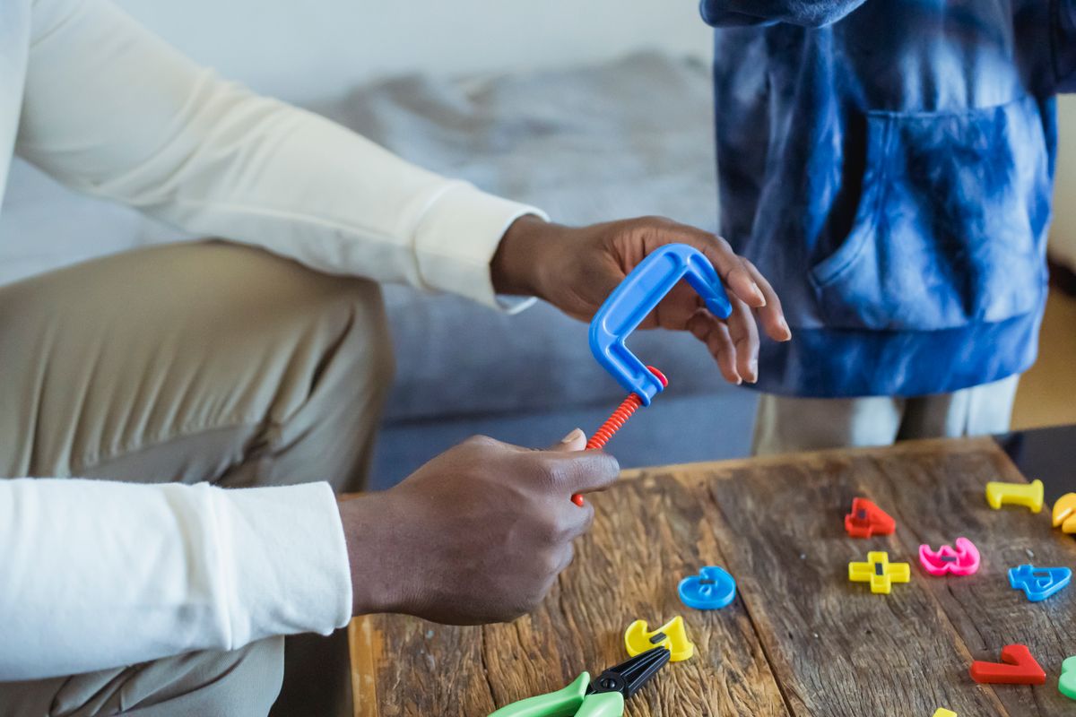 High angle of crop anonymous dad playing with toy instrument while spending time with son