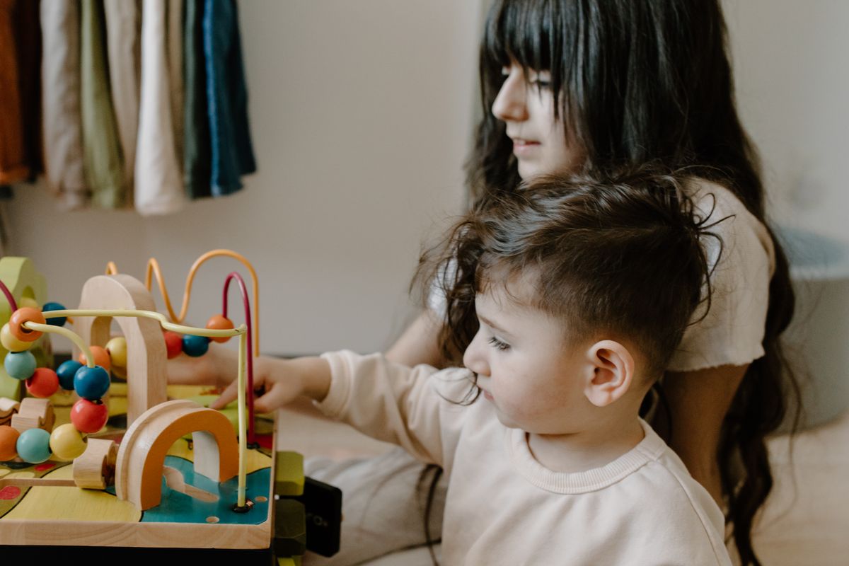 Two children engaged with wooden toys at a table, fostering imagination and playtime.