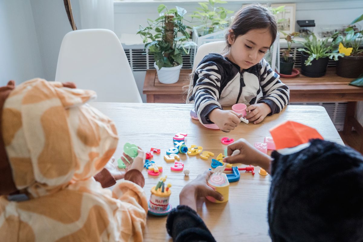Children enjoying playtime in animal onesies with toys at home.