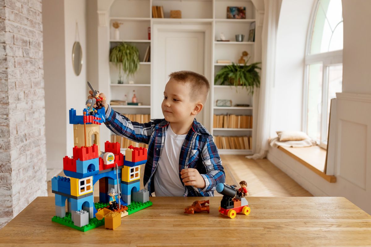 A young boy enjoying building a colorful block castle indoors, showcasing creativity and play.