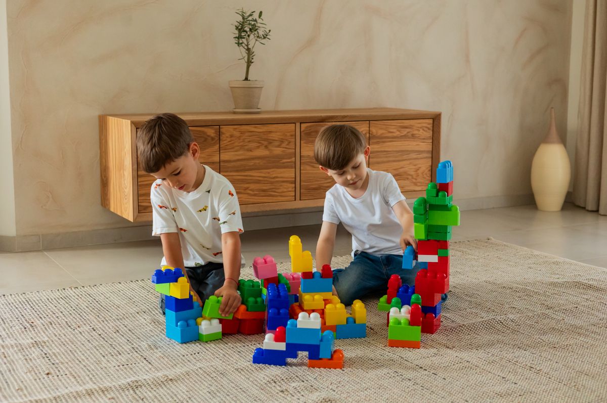 Two boys enjoy building with colorful toy blocks in a cozy living room setting.